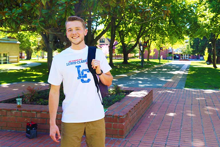 A smiling student in front of a low brick wall