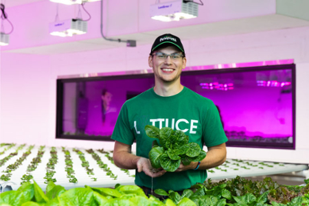 A student holds a head of lettuce in an agriculture building at University of Wisconsin Platteville